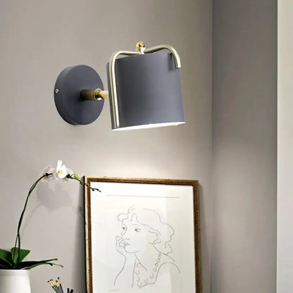 Green gray metal wall sconce with brass curved arm and gray shade on circular backplate on Tampa Home & Garden Store