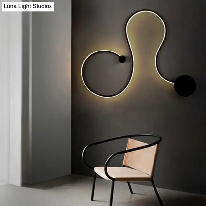 Black metal wall sconce with illuminated white edge and twist loop silhouette by Decorbites on Tampa Home & Garden Store