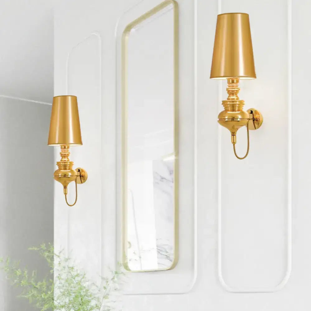 Pair of brass wall sconces with gold tapered lampshades flanking a tall mirror on a white wall on Tampa Home & Garden Store