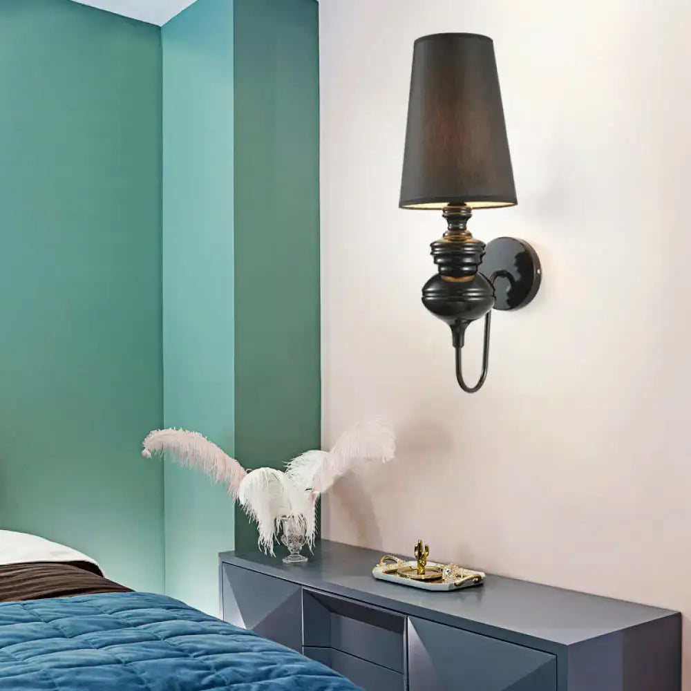Contemporary black metal wall sconce with a tapered shade and round backplate on Tampa Home & Garden Store
