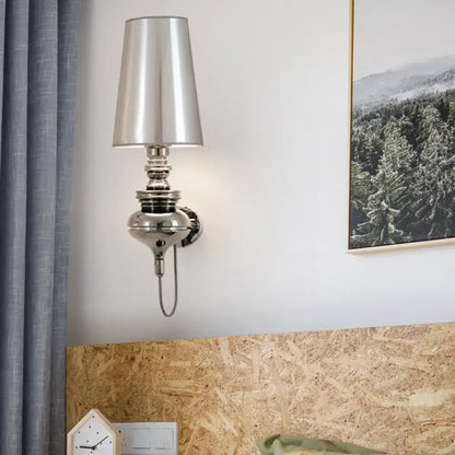 Contemporary chrome wall sconce with a tapered silver shade and decorative base in a bedroom on Tampa Home & Garden Store