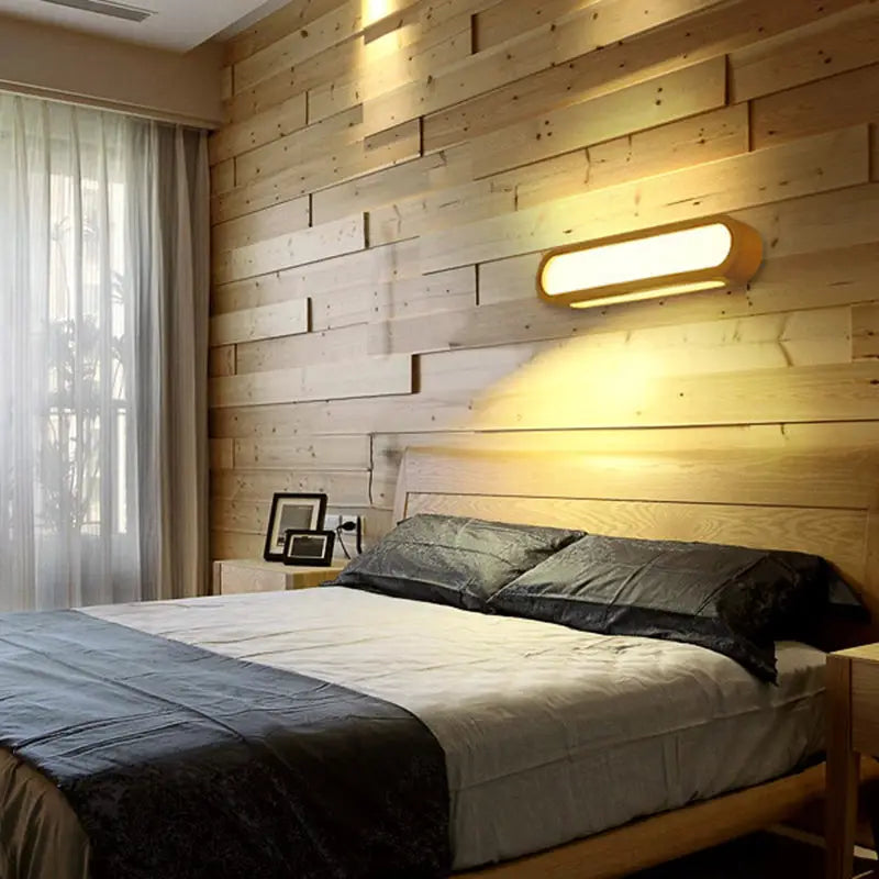 Wood LED elongated 25-inch vanity light with warm glow on a wood-paneled bedroom wall above the bed on Tampa Home & Garden Store