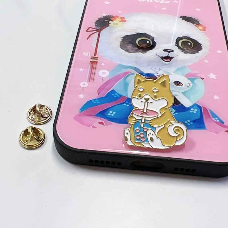 Gold-tone corgi drinking boba enamel pin on pink phone case with panda art on Tampa Home & Garden Store