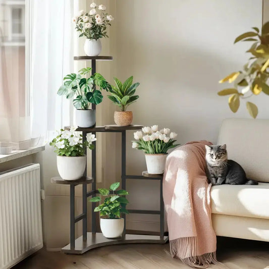 Black metal corner plant stand with wood shelves hosting several plants in a bright living room on Tampa Home & Garden Store