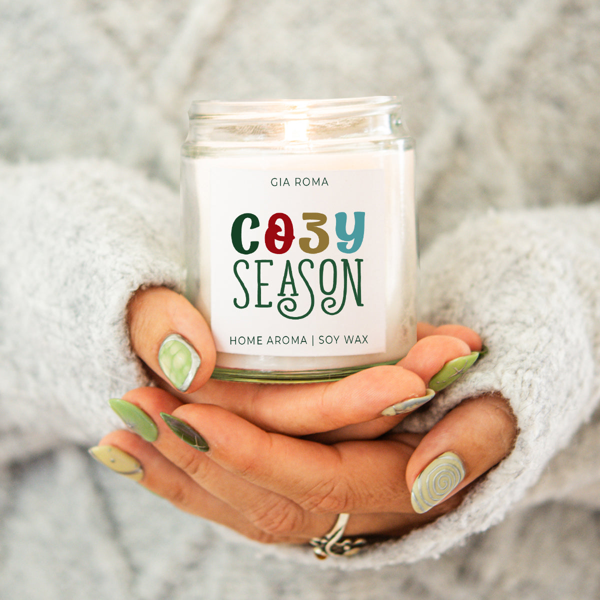 Cozy Season candle by Gia Roma; white soy wax in a clear jar held in a grey knit sweater on Tampa Home & Garden Store