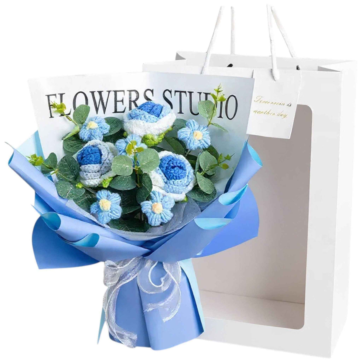 Crochet rose bouquet with blue blooms and green leaves in blue wrapping beside a gift bag on Tampa Home & Garden Store
