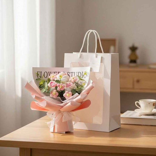 Crochet Rose Bouquet with LED Light by Shaketea, pink wrap and white ribbon beside a gift bag on Tampa Home & Garden Store