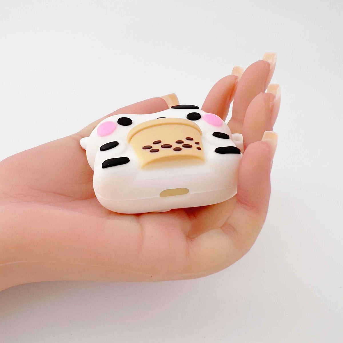 Milk Cow Boba AirPods Case, white silicone with pink cheeks, held in hand on Tampa Home & Garden Store