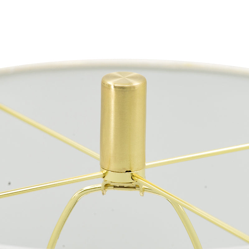 Gold metal table lamp with cylindrical finial and radiating arms above a glass shade on Tampa Home & Garden Store