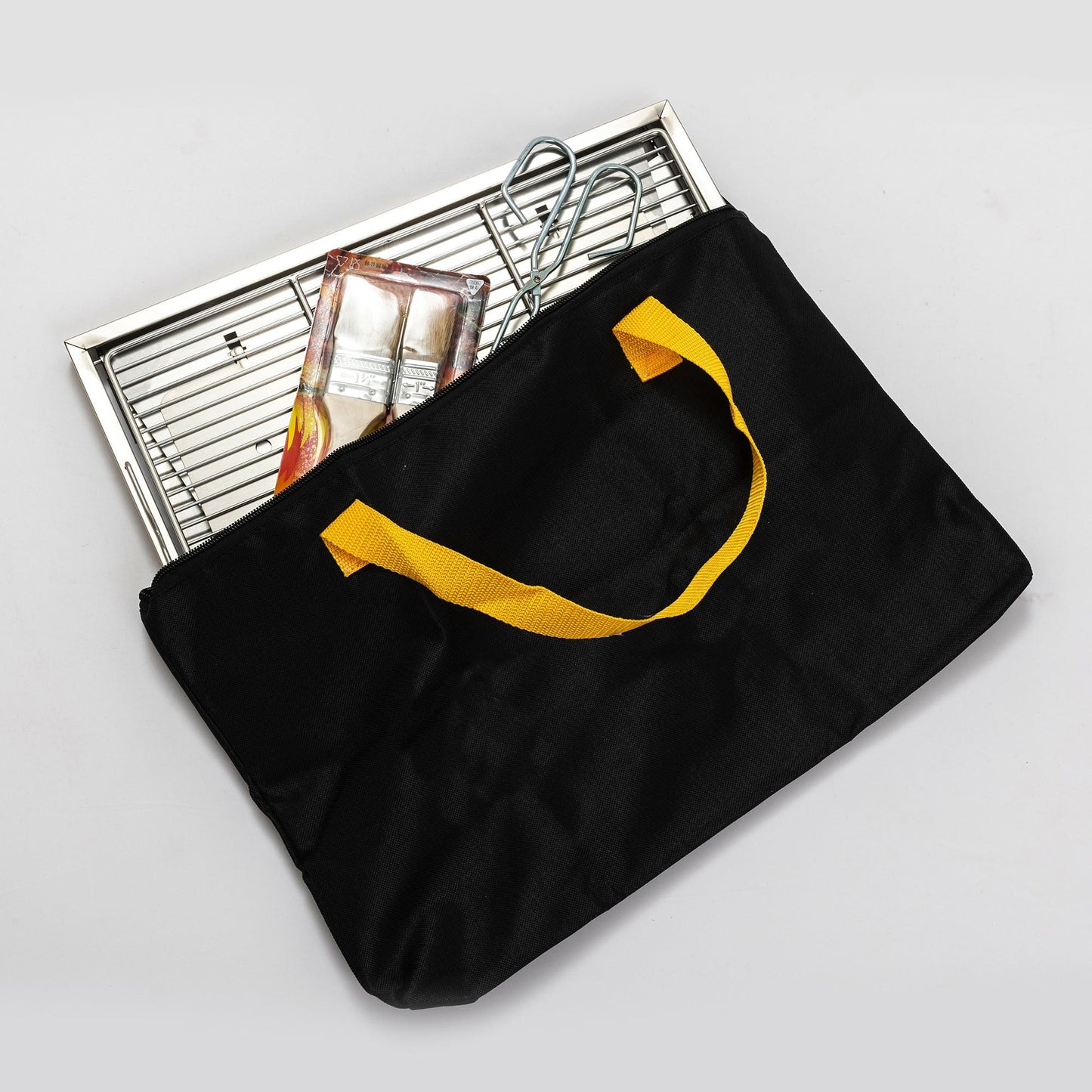 Folded portable BBQ grill set with stainless rack in a black bag with yellow straps on Tampa Home & Garden Store