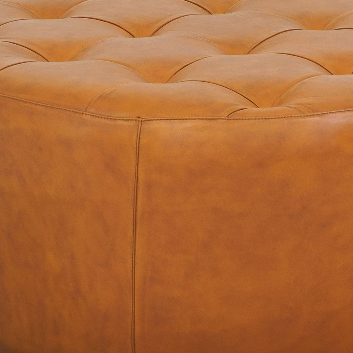 Light tan leather ottoman with tufted surface and stitched seams on Tampa Home & Garden Store