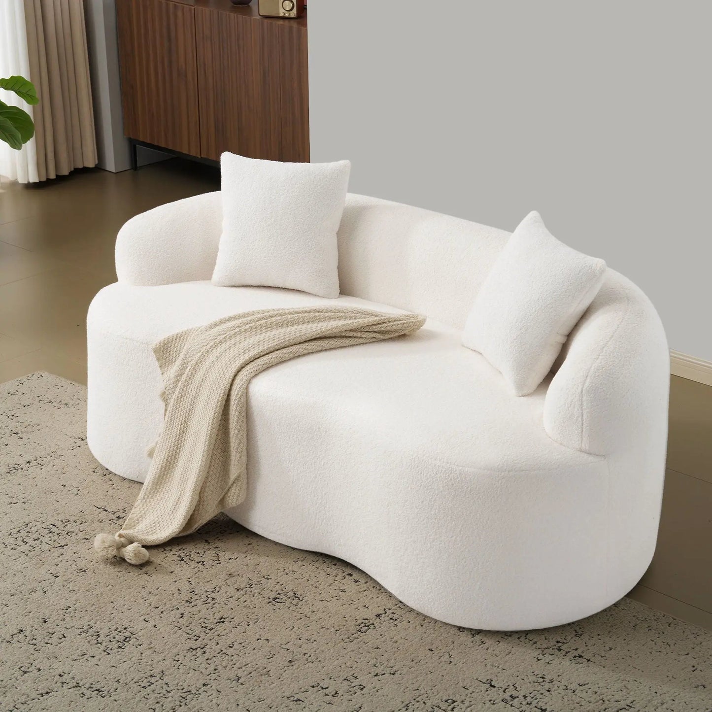 Curved loveseat sofa in white boucle fabric with round arms; beige knit blanket draped on Tampa Home & Garden Store
