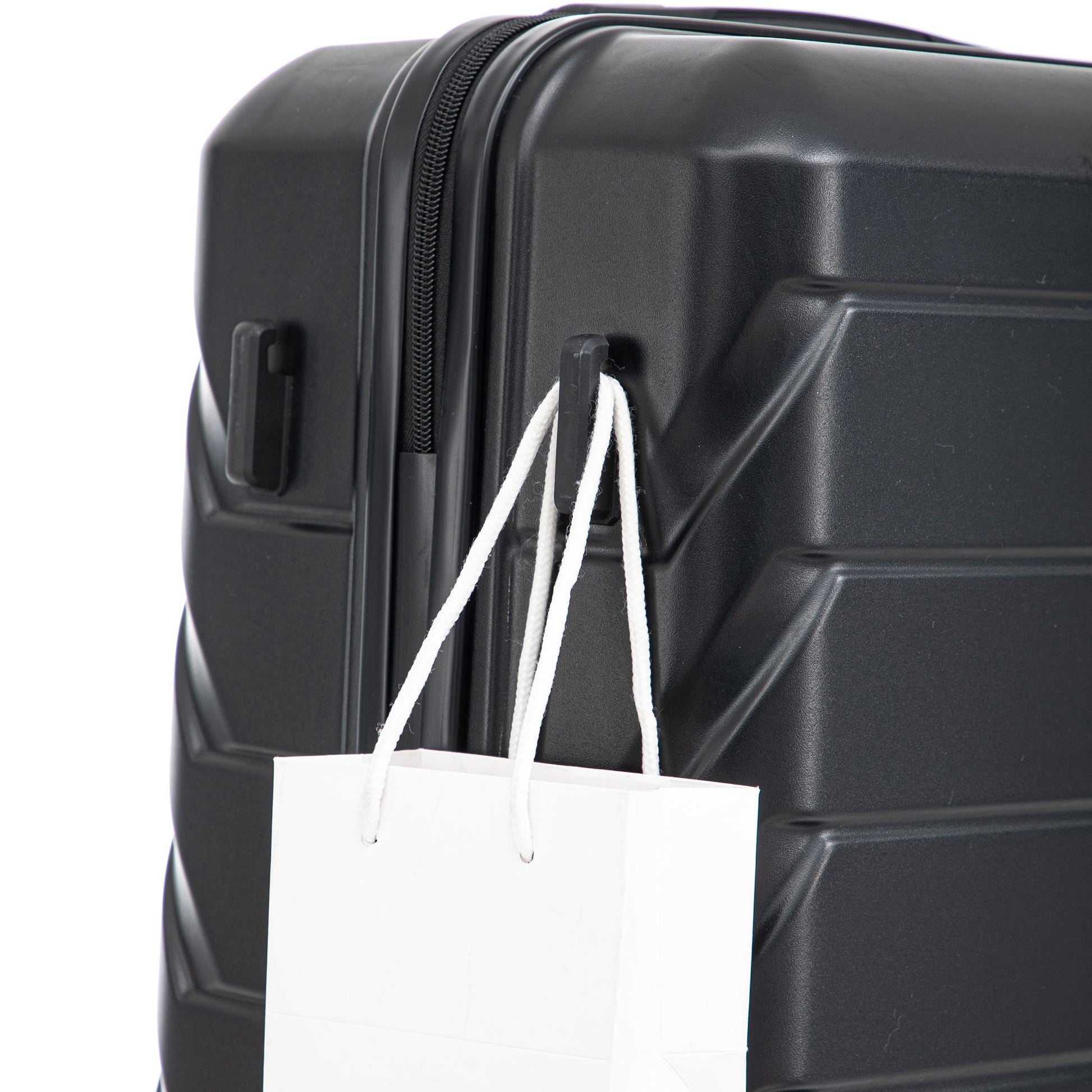 Black hard-shell luggage close-up with zipper edge and white shopping bag attached on Tampa Home & Garden Store
