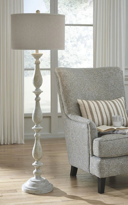 Bernadate poly floor lamp whitewash finish with beige drum shade beside a patterned chair on Tampa Home & Garden Store