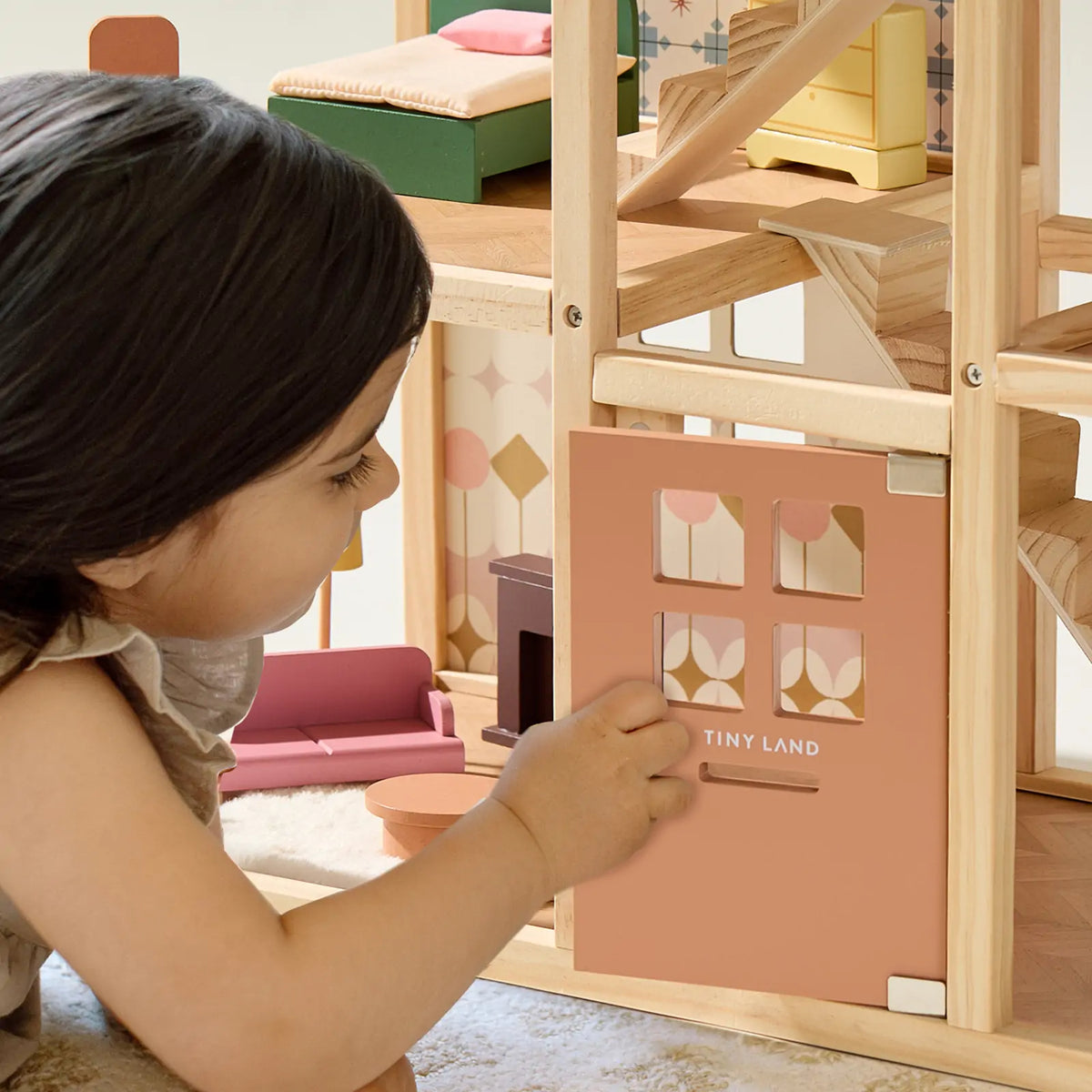 Tiny Land Sweetwood Pegasus Dollhouse with wooden frame and pink facade; child plays with minis on Tampa Home & Garden Store