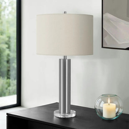 Contemporary table lamp with brushed metal stem, clear acrylic base, and beige fabric shade on Tampa Home & Garden Store