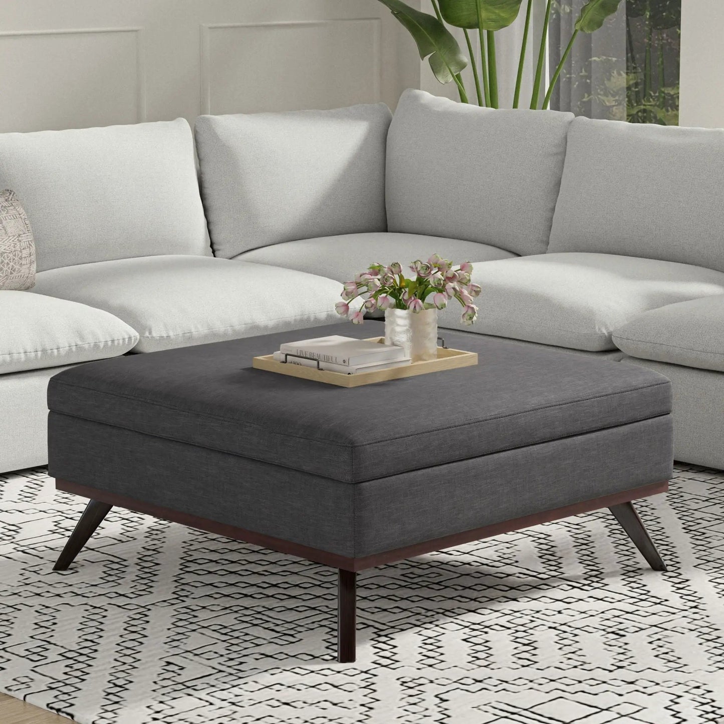 Owen square coffee table storage ottoman in dark gray fabric with wood legs and tray of books on Tampa Home & Garden Store