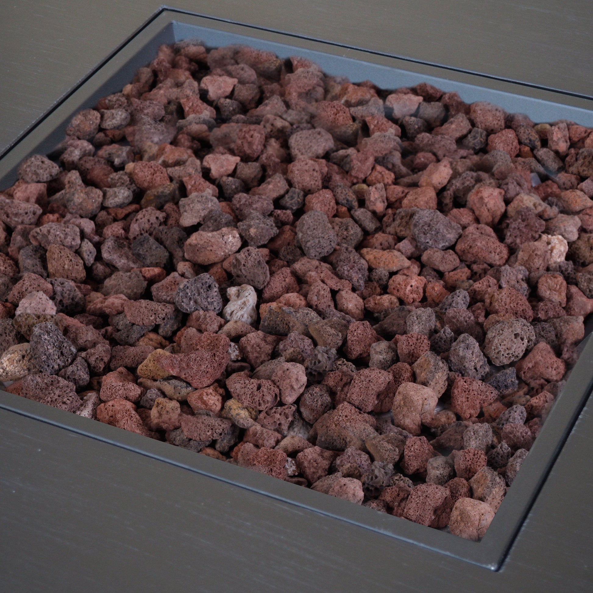 Outdoor propane fire pit with square iron frame filled with red lava rocks on Tampa Home & Garden Store