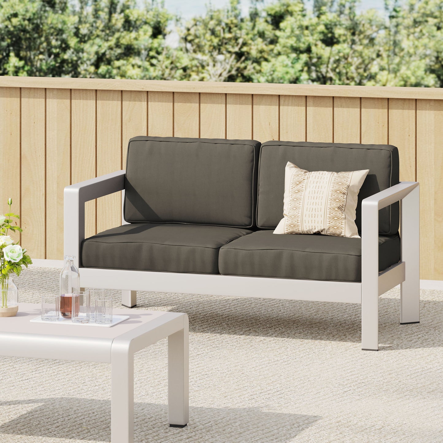 Outdoor aluminum loveseat with low-profile white frame and deep charcoal cushions on Tampa Home & Garden Store