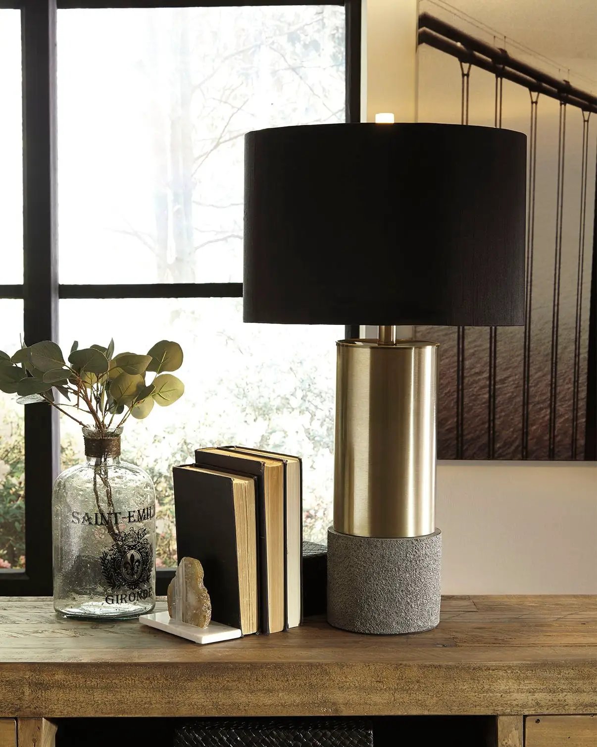 Jacek metal table lamp with black drum shade, brass cylindrical base atop concrete pedestal on Tampa Home & Garden Store