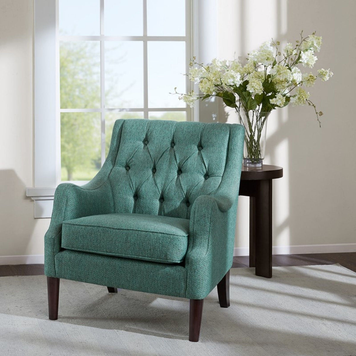 Teal button tufted accent chair with solid wood legs beside a dark side table on Tampa Home & Garden Store