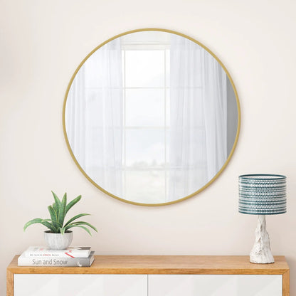 Round wall mirror with a gold metal frame mounted on a pale wall in a stylish living room setup on Tampa Home & Garden Store