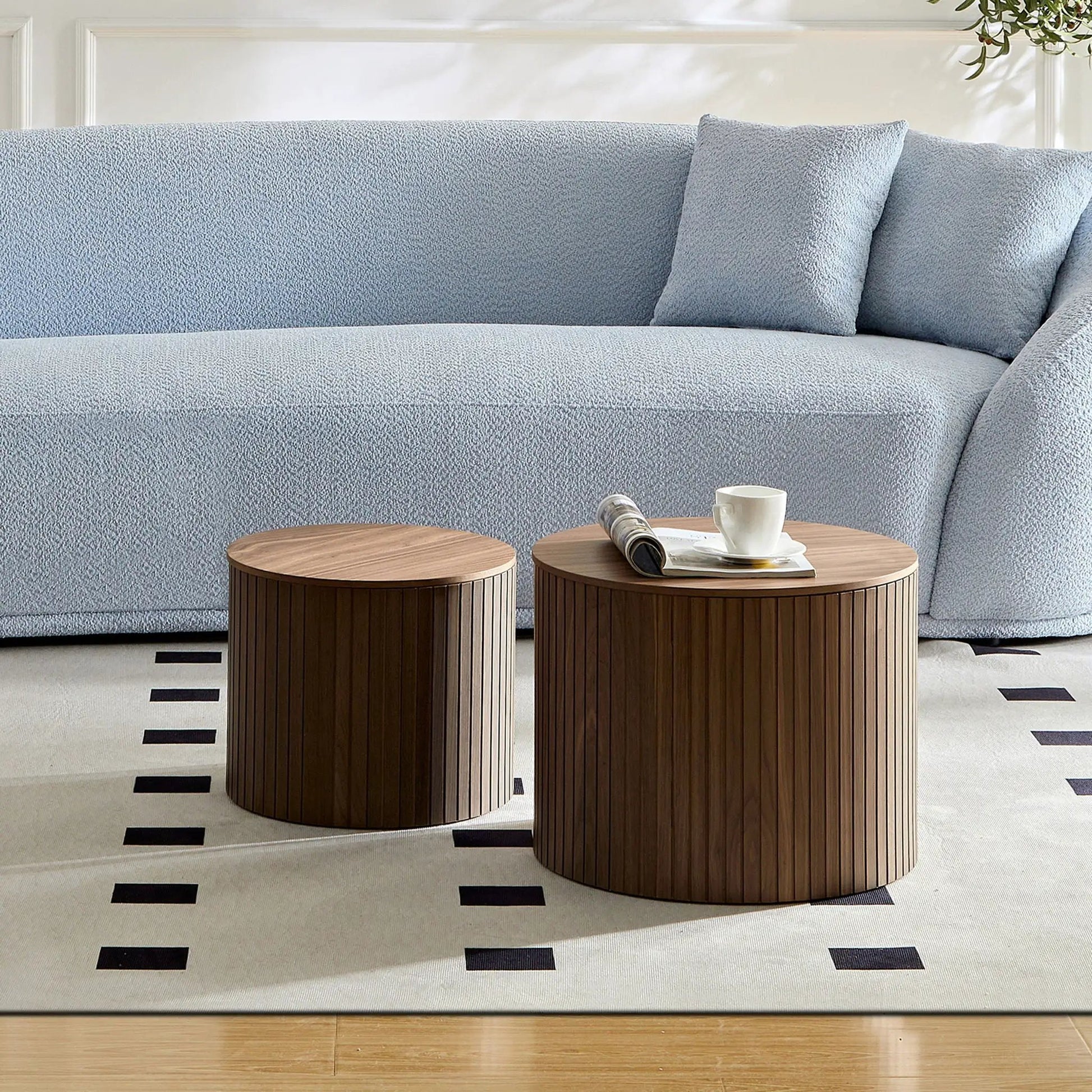 Handcrafted 2-piece nesting table set in dark wood with ribbed bases beside a blue sofa on Tampa Home & Garden Store