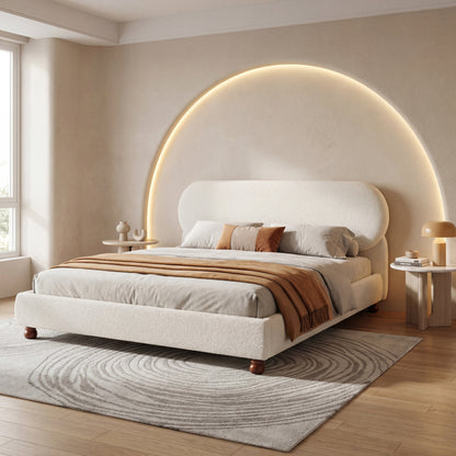 Cream bouclé upholstered king bed with rubber wood feet, curved padded headboard and warm arched wall lighting on Tampa Home & Garden Store