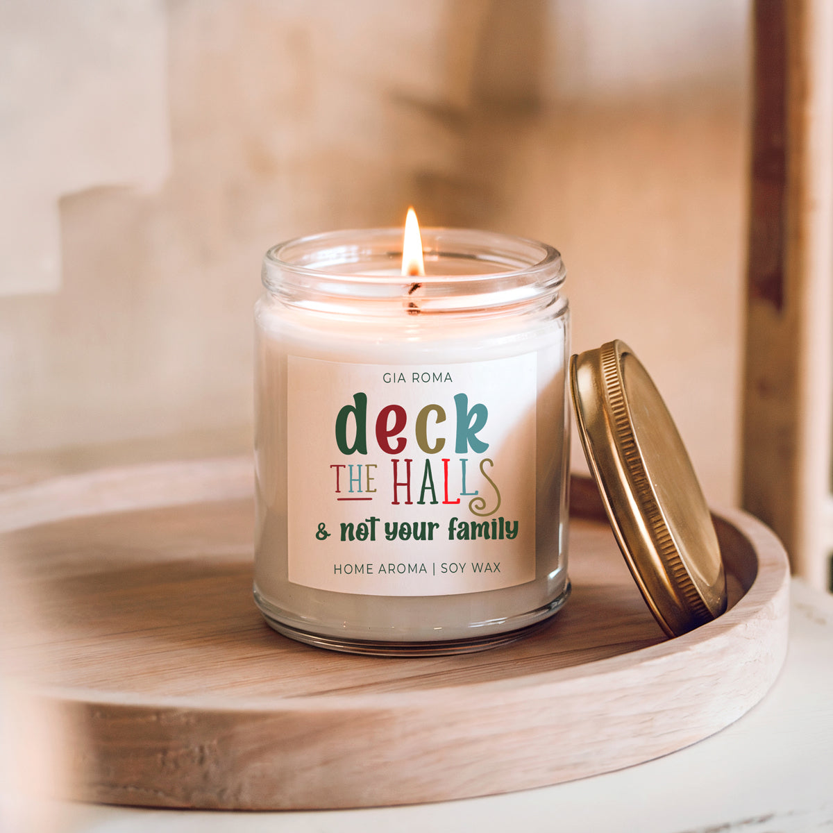 Deck The Halls candle by Gia Roma, soy wax in a clear glass jar with a gold lid on a wooden tray on Tampa Home & Garden Store