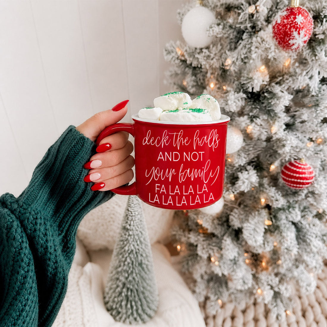 Deck The Halls Gia Roma mug, red ceramic with white script, marshmallow-topped, tree backdrop on Tampa Home & Garden Store