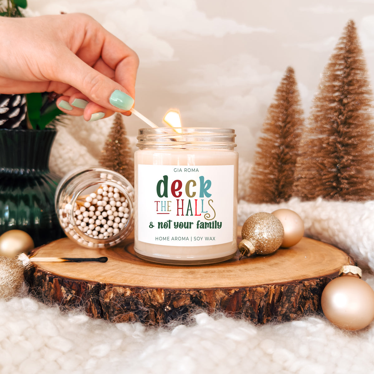 Deck The Halls candle Gia Roma, soy wax in a glass jar, lit on a wood slice with ornaments on Tampa Home & Garden Store