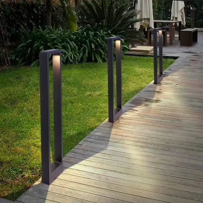 Three modern black LED aluminum garden bollard lights along wooden walkway on Tampa Home & Garden Store