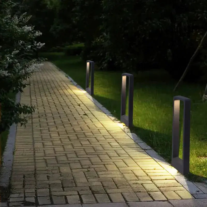 Modern black LED aluminum garden bollard lights set of 3 along brick path with warm glow on Tampa Home & Garden Store