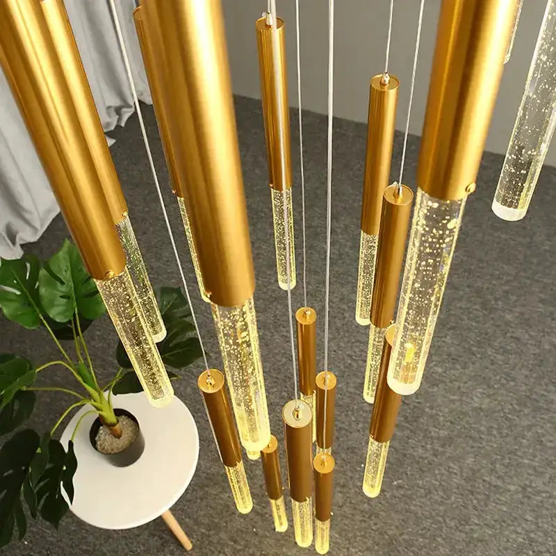 Modern gold crystal chandelier with multiple cylindrical pendant tubes, warm LED glow on Tampa Home & Garden Store