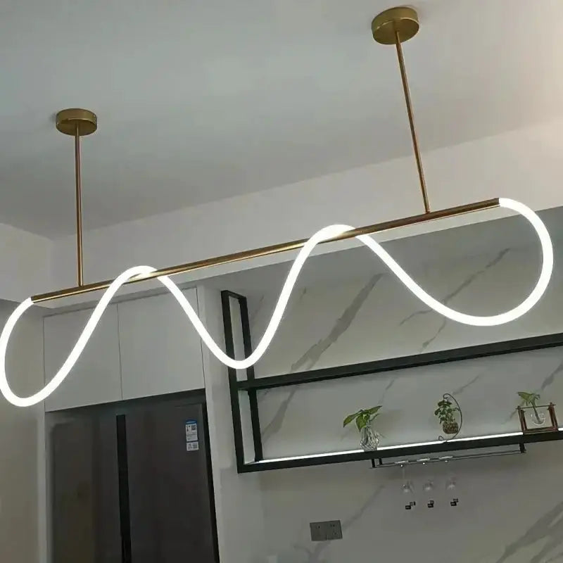 Modern gold curved LED chandelier pendant light with a wavy neon loop over a brass bar on Tampa Home & Garden Store
