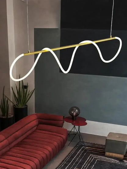 Decorbites modern gold curved LED pendant chandelier over red sofa in chic living room on Tampa Home & Garden Store