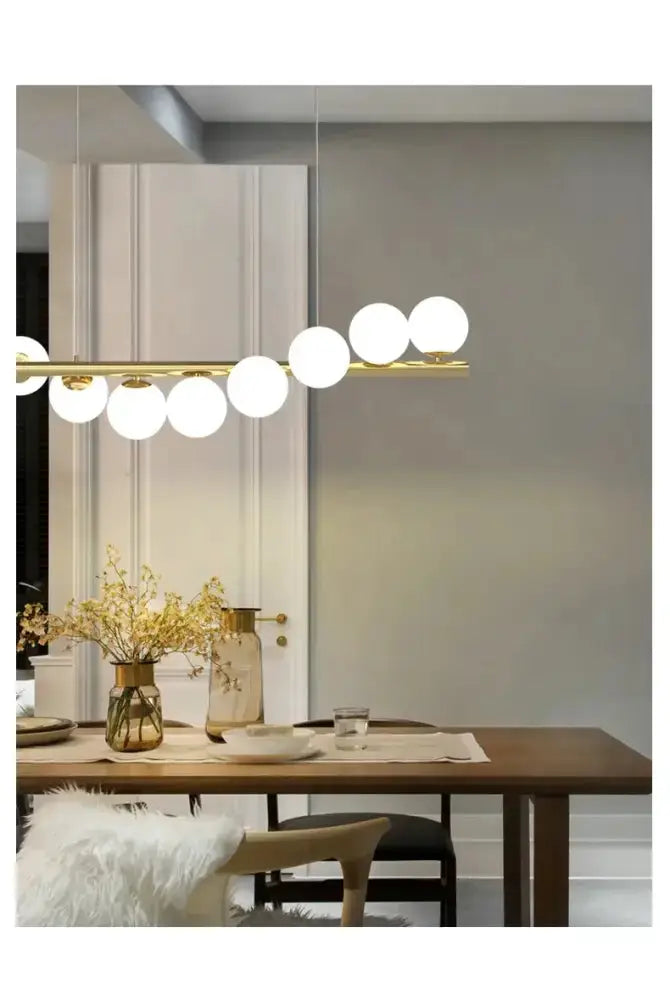 Modern gold long ceiling chandelier with glass globe pendants over dining table Decorbites on Tampa Home & Garden Store