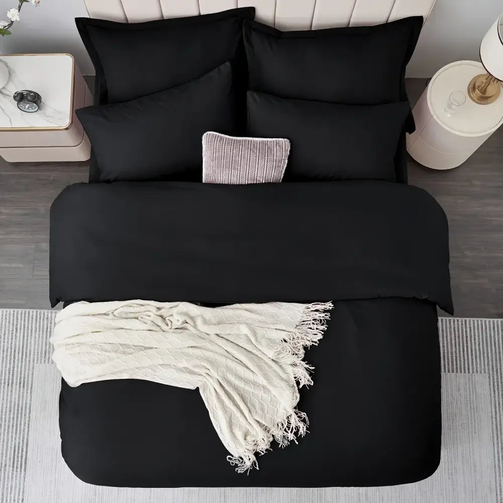 Black satin duvet set on a bed with black pillow shams and a cream textured throw blanket on Tampa Home & Garden Store