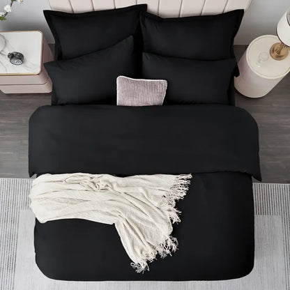 Black satin duvet set on a bed with black pillow shams and a cream textured throw blanket on Tampa Home & Garden Store