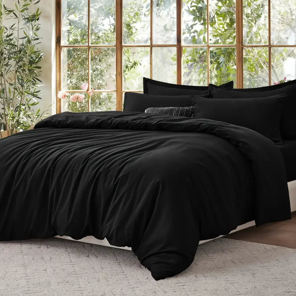 Black satin duvet set with matching black pillow shams on a bed in a sunlit room on Tampa Home & Garden Store