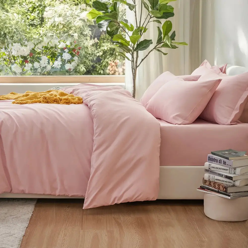 Decorbites pink satin duvet set on bed with matching pink pillows beside a plant and books on Tampa Home & Garden Store