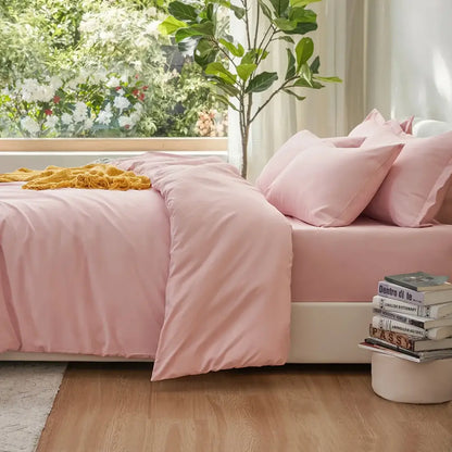 Decorbites pink satin duvet set on bed with matching pink pillows beside a plant and books on Tampa Home & Garden Store