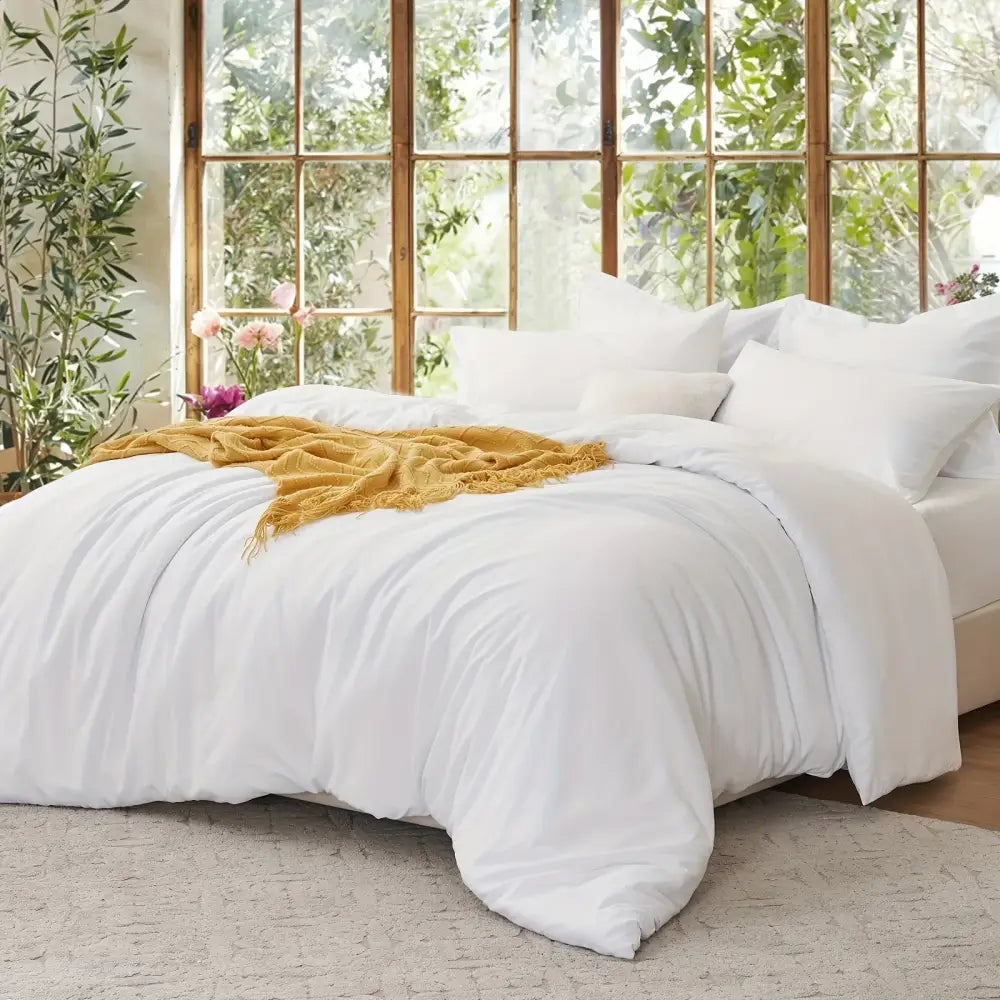 Decorbites Black Satin Duvet Set on bed with white linens and a mustard throw in a bright room on Tampa Home & Garden Store