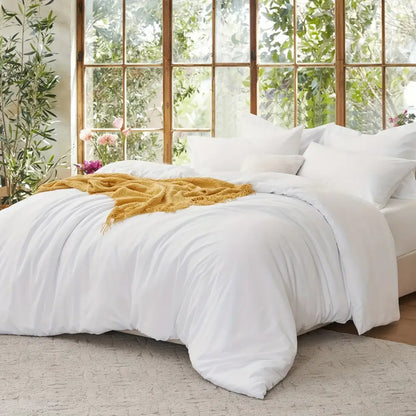 Decorbites Black Satin Duvet Set on bed with white linens and a mustard throw in a bright room on Tampa Home & Garden Store