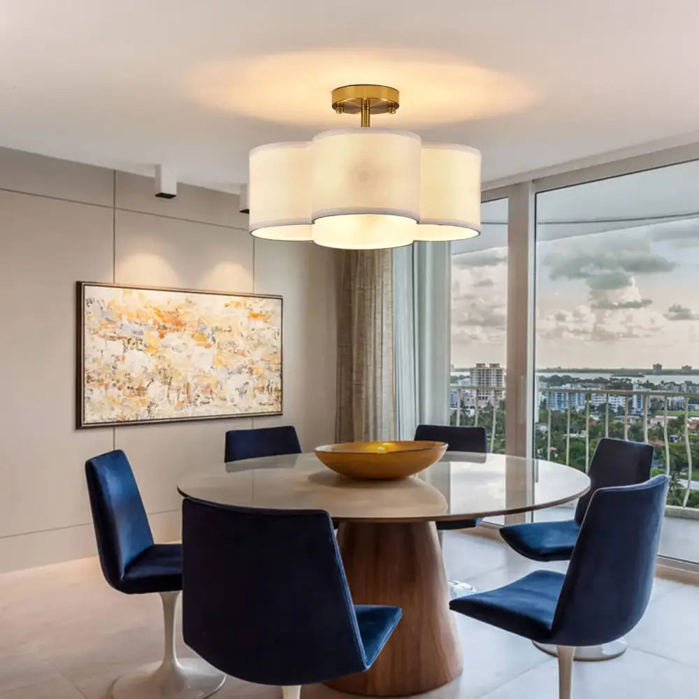 Gold 4-light flush mount ceiling fixture by Decorbites with frosted drum shades above dining table on Tampa Home & Garden Store