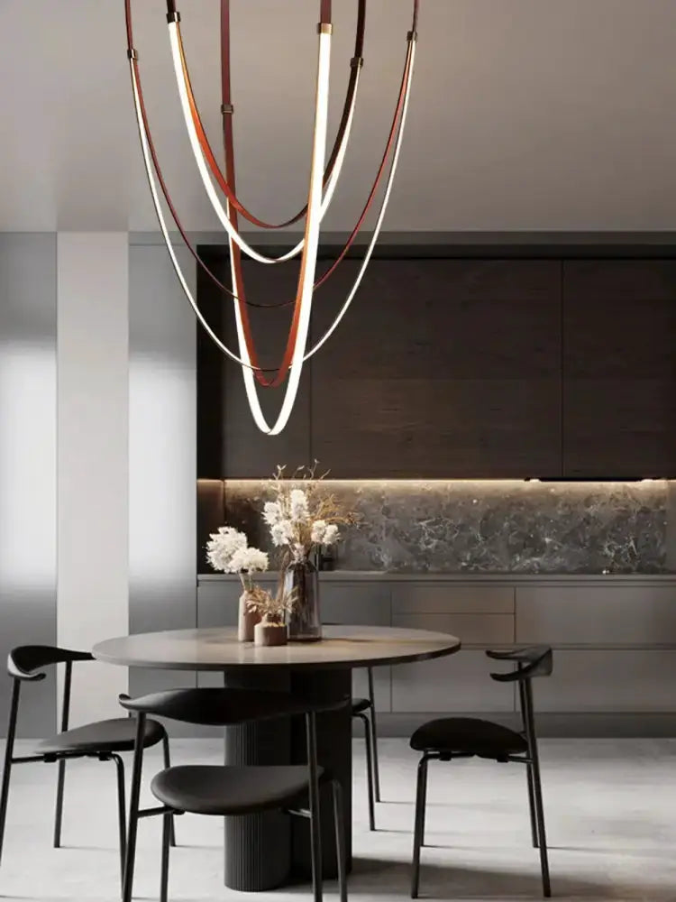 Modern flexible leather belt LED chandelier with copper-toned loops above a round dining table on Tampa Home & Garden Store