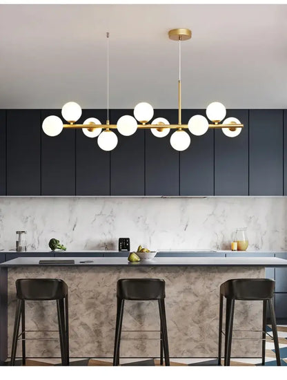 Gold Glass Ball Chandelier Decorbites with brass bar and white globes over marble island on Tampa Home & Garden Store