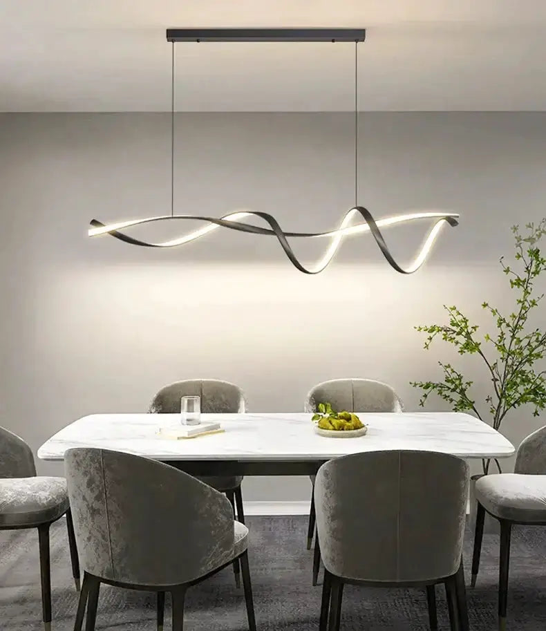Modern black and gold wave LED glass pendant light above a marble dining table with grey chairs on Tampa Home & Garden Store
