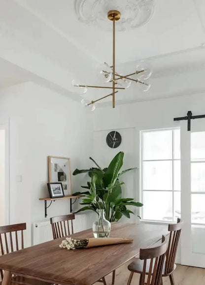 Decorbites modern gold glass bubble starburst chandelier hanging over a wooden dining table on Tampa Home & Garden Store