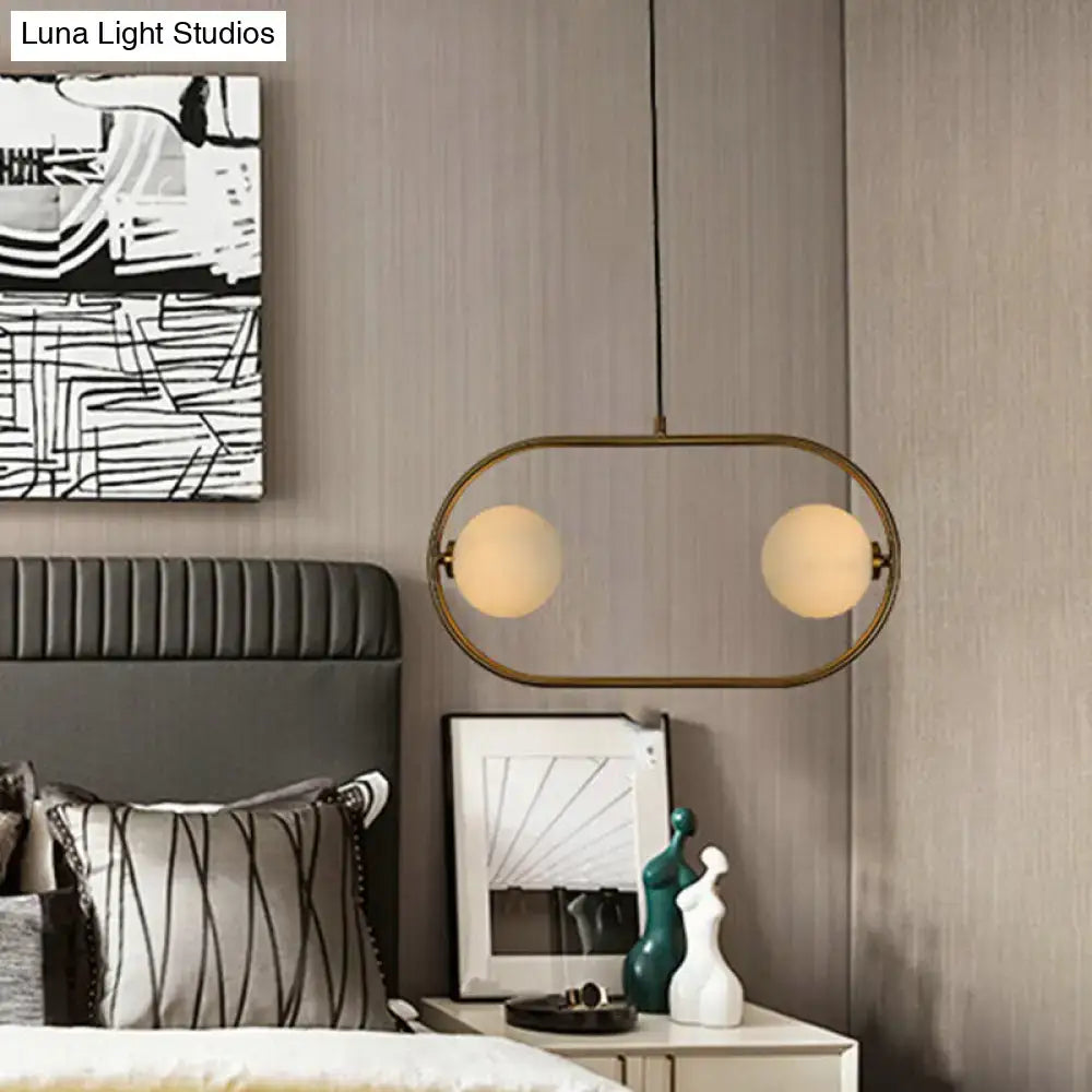 Gold globe hanging chandelier with an oval brass frame and two frosted glass spheres on Tampa Home & Garden Store